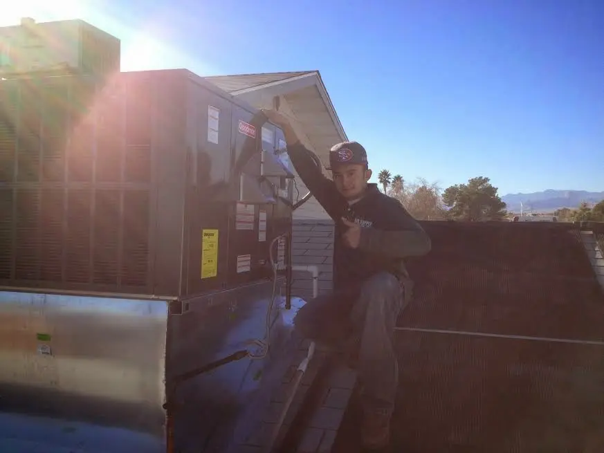 HVAC technician performing AC Tune-Up on a rooftop unit in Desert Palms